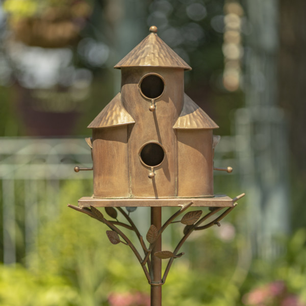 Copper triple cylinder conical roof birdhouse stake with vines and leaves running under the bottom rim of the birdhouse holding it up and there are circular holes on the birdhouse for birds to enter