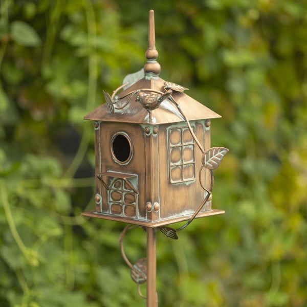 Close up image of Tall chapel birdhouse garden stake with vines running on it and mini bird at the top on the roof