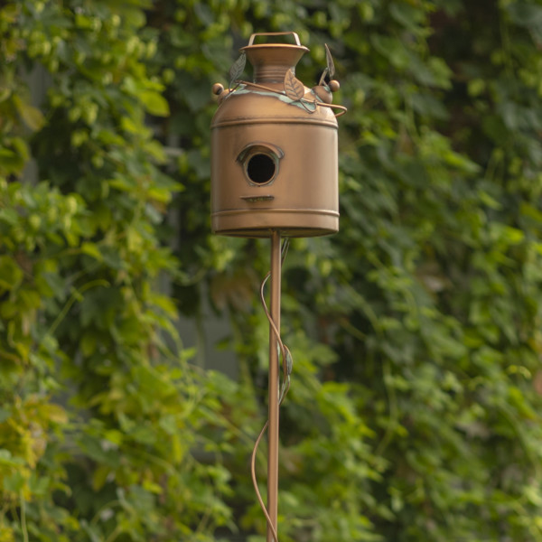 Close up image of Tall birdhouse stake shaped like a milk can with vines running from the bottom of the stake to the top of the birdhouse