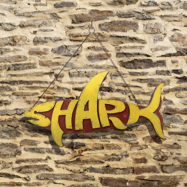 Hanging metal shark sign in yellow and dark red distressed finish on a wall