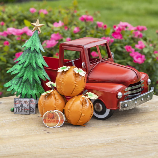 small vintage red iron pickup truck with three pumpkins, Christmas tree and seasonal decimals in front of it