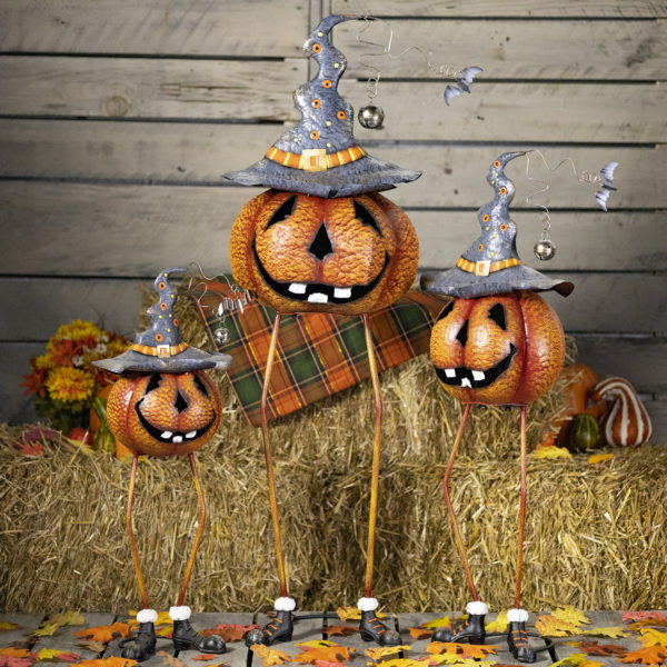 3 long legged jack-o-lantern pumpkins wearing witch hat Halloween figurines in front of haystacks