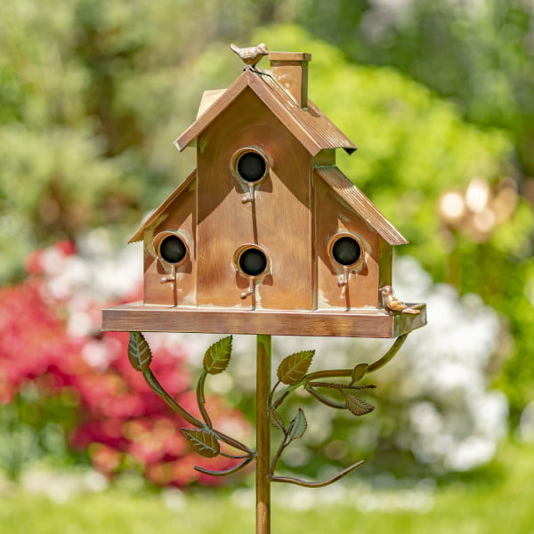 Metal multi-family birdhouse stake in a classic style with short chimney and little bird perched on top of it painted in antique copper finish with patina accents