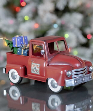 Side view of small metal Red Vintage Style Truck with Christmas gifts and trees in the back