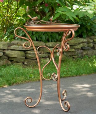Shallow tray copper birdfeeder with three curlicue legs and two birds perched to the top of the birdfeeder