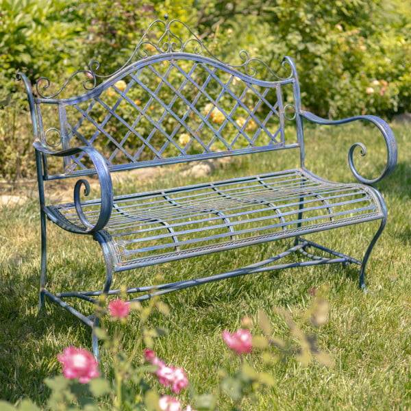Side view of Victorian style iron garden bench in antique blue distressed finish with exquisite lattice backrest with filigree details juxtaposed with the perpendicular slats of the seat in garden