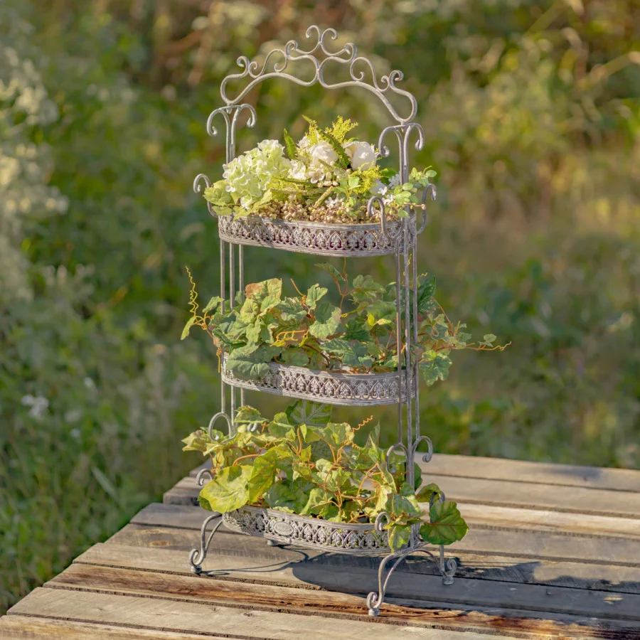 Side view image of the Antique Grey three tier Plant Stand with curlicue designs at the top, sides and bottom of the item