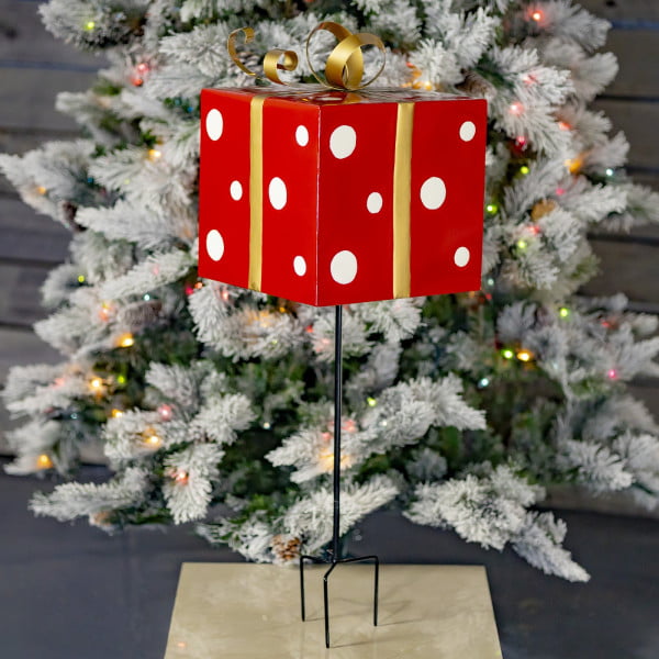 32 inch tall red and white polka dot pattern metal Christmas gift box three prong yard stake with metallic gold ribbon in front of light-up tree