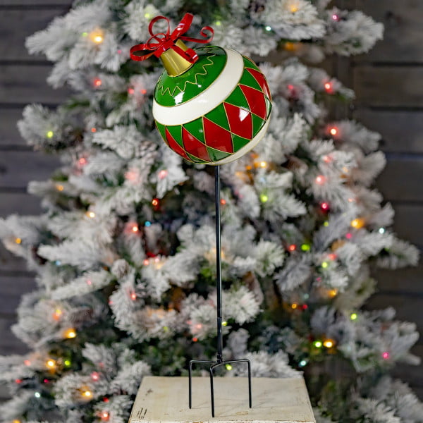 Large Metal Christmas Ball ornament on a tall stake in front of light-up Christmas tree