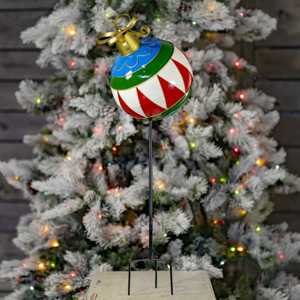 31 inch tall multi-colored metal Christmas ball ornament yard stake with metallic gold ribbon bow on top in front of light-up tree