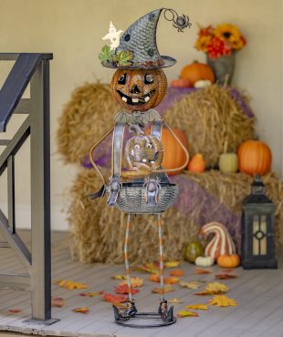 Halloween lantern decoration with tall iron pumpkin witch with inner body shaped into a candy holder standing on doorstep