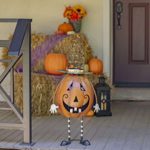Halloween decoration of a standing pumpkin with two legs and two hands wearing a light up LED witch's hat