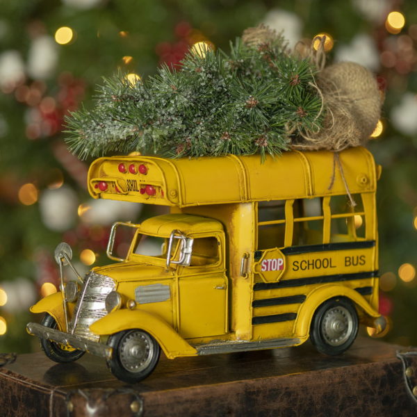 side view image of metal vintage style small school bus with Christmas tree on top of it
