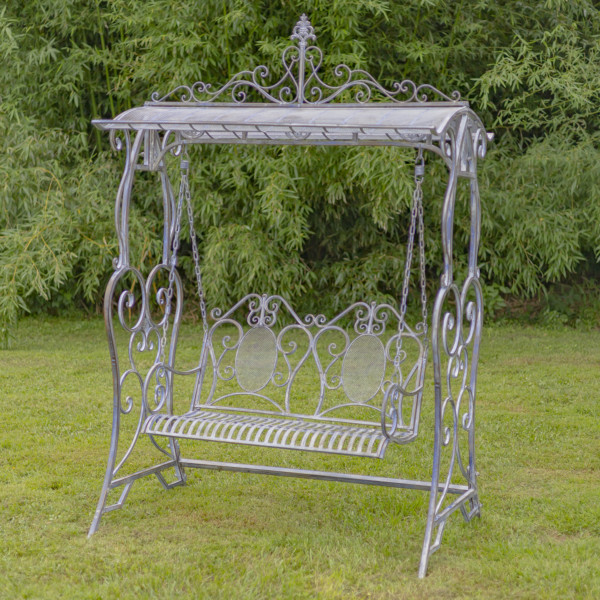 A large iron swing bench in blue bronze with curlicue designs on both ends of the swings , the backrest also has a curlicue design as well as the the top of the sheltered roof on the swing bench