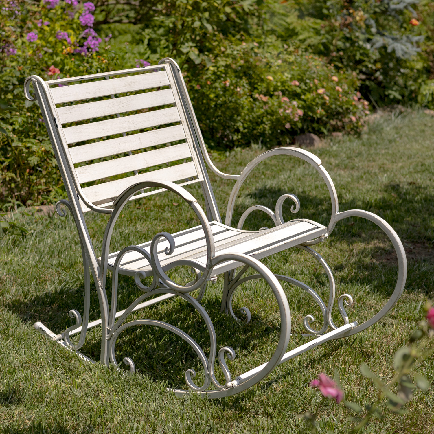 Side image of Antique white iron rocking arm chair with curlicue dedigns on the side