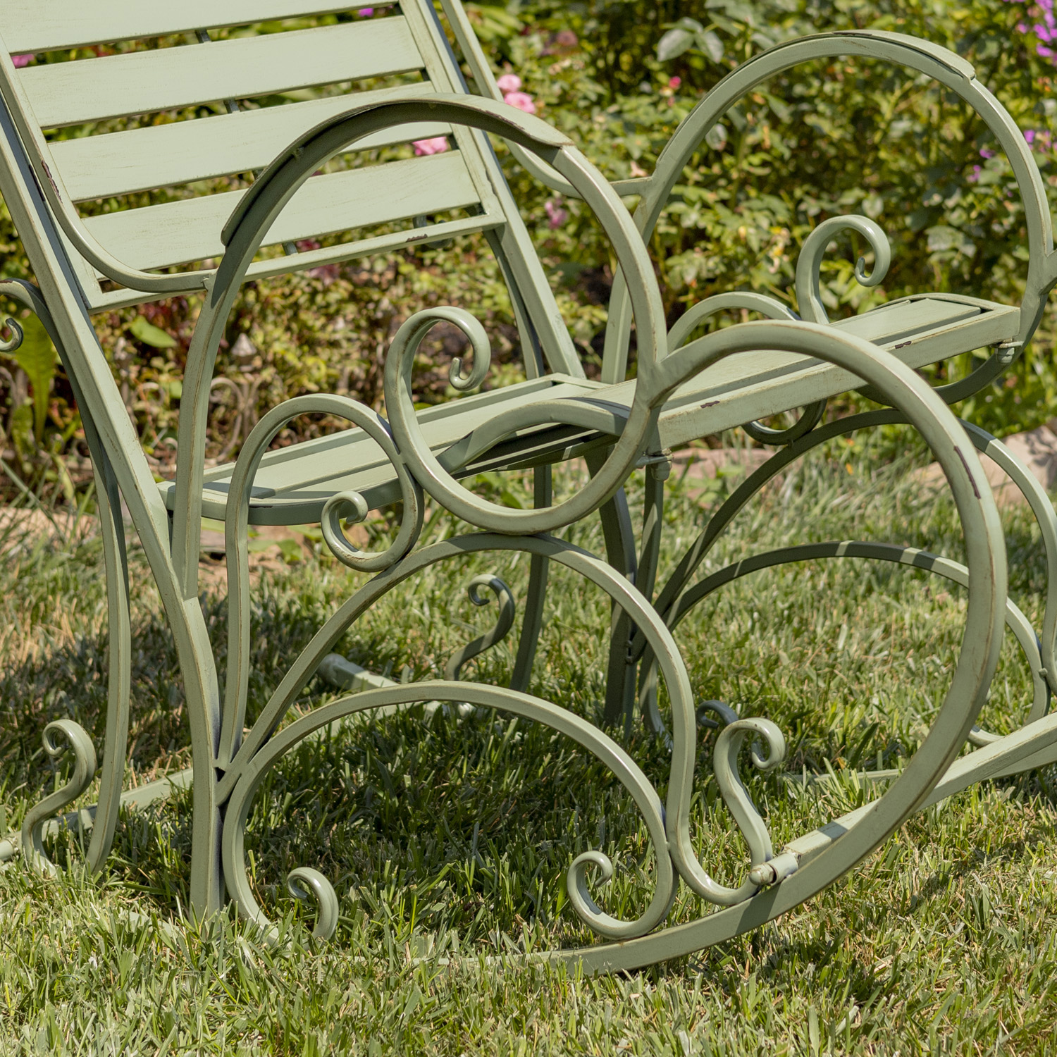 Close up image of the curlicue desighn on the side of the green iron armchair