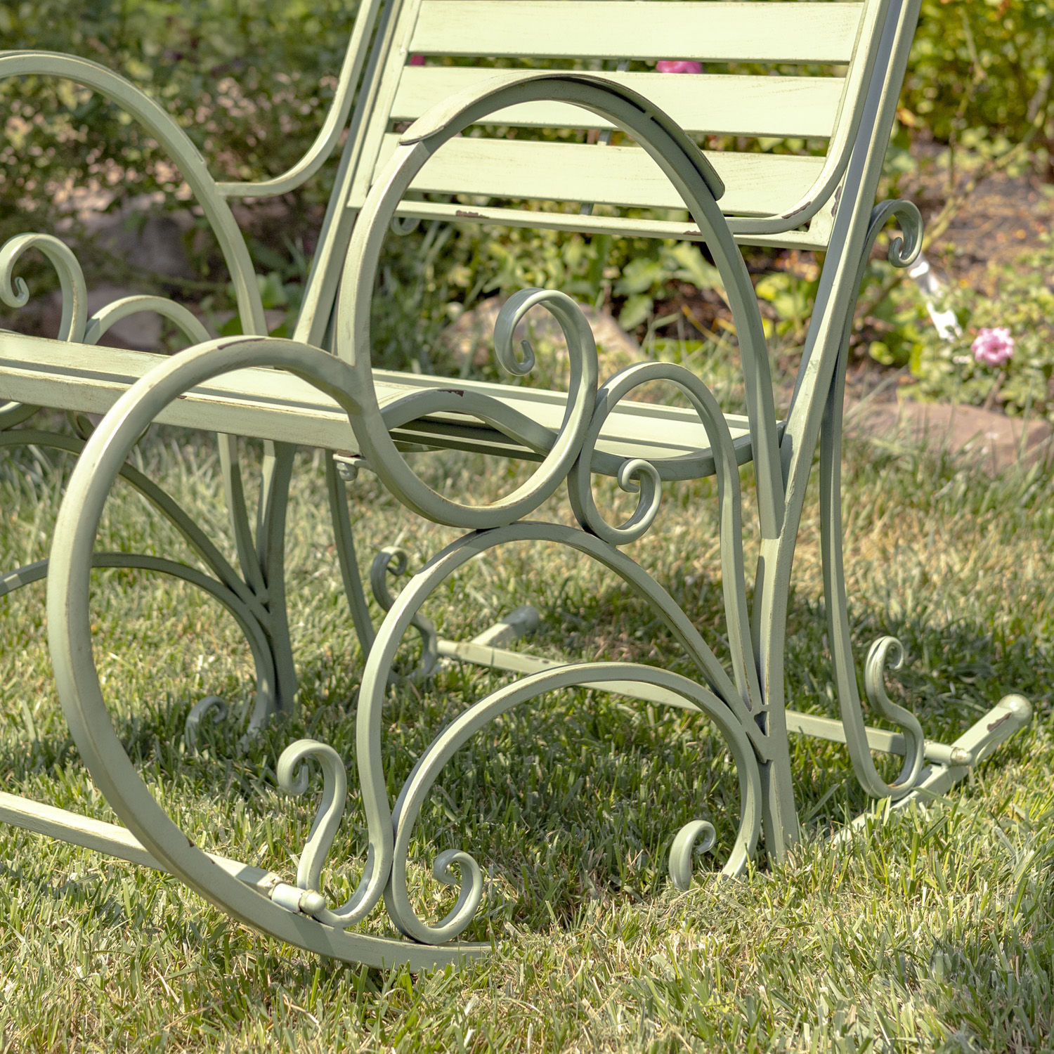 Close up image of the curlicue desighn on the side of the Antique green iron armchair