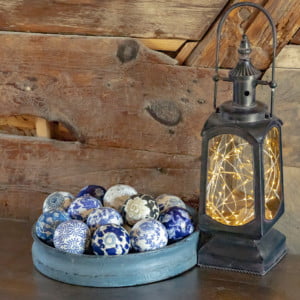 Twelve Ceramic Balls in a Round Tray next to a Lantern