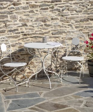 Antique white metal bistro set that includes two chairs and a table with curlicue designs