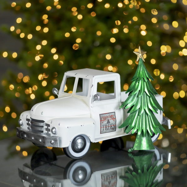 Small iron Christmas old style truck with decimal on a door next to tree in antique white finish