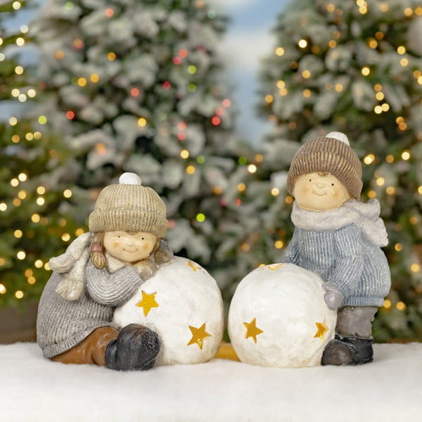 boy and girl figurines in winter clothes playing snowballs lanterns with star cutouts