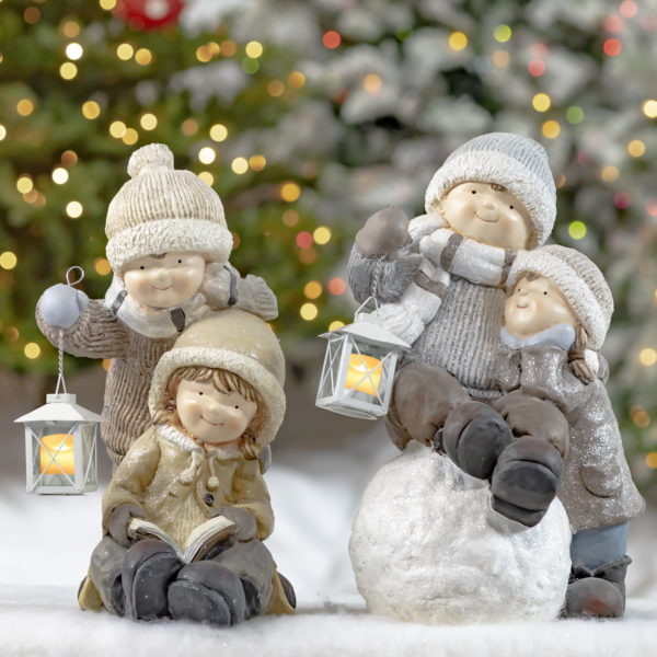 2 Sets of Children Statues- Sitting on a Snowball, Holding Lanterns and Reading a Book- Christmas Tree lights in the background of picture
