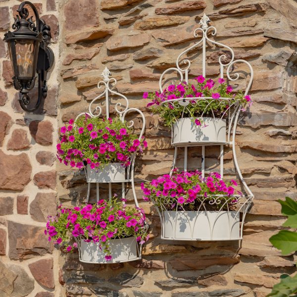 Two dual white hanging on wall iron basket planters with curlicue designs and plants in it for additional décor ( Plants not included)