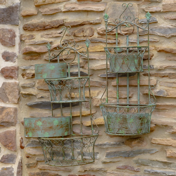 Side view of set of 2 dual half moon-shaped wall hanging planters with removable baskets in verdi green distressed finish on a brick wall