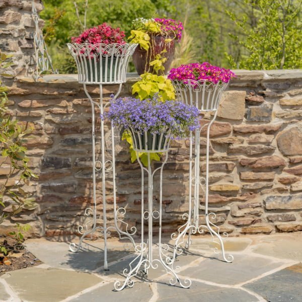 set of three assorted height iron plant stands with a distressed Antique White finish full of beautiful vibrant flowers