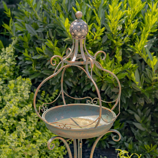 Close up image of Tall standing bronze iron birdbath with brown ceramic floral designed ball