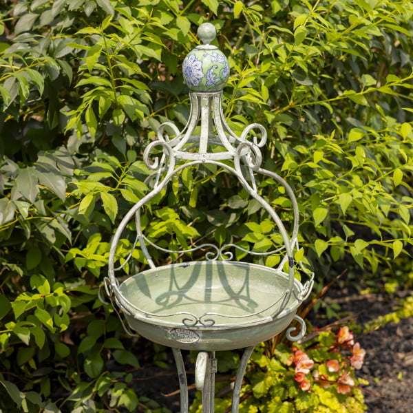 Close up image of Tall standing green iron birdbath with green ceramic floral designed ball
