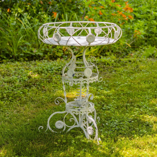 Iron round Victorian style planter table featuring aster blossom and rope-like twisted metal pattern in antique white distressed finish in garden