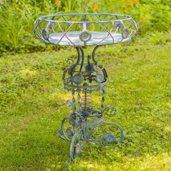 Iron round Victorian style planter table featuring aster blossom and rope-like twisted metal pattern in cobalt blue distressed finish in garden