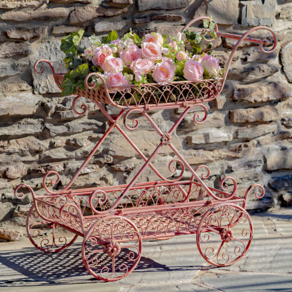 Flamingo red two tier flower push cart with four moving wheels and curlicue designs with pink flowers in it ( Flowers not included)