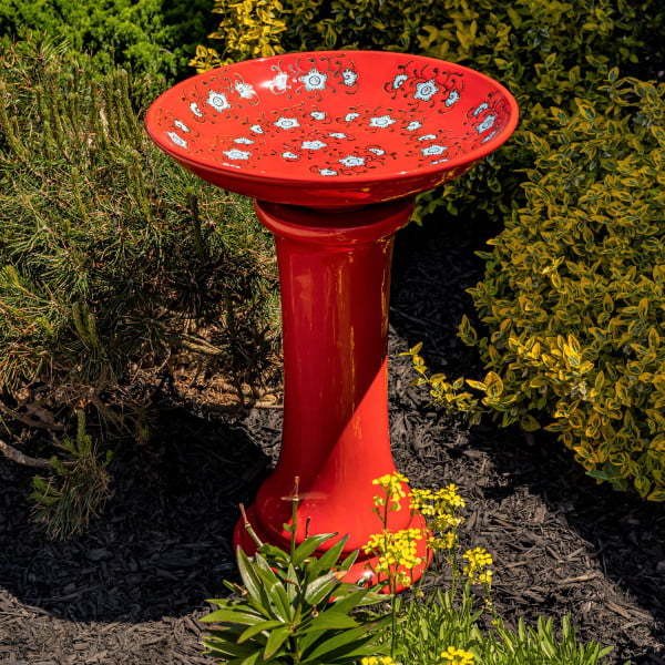 24 inch tall red porcelain pedestal birdbath with baby blue flower blossoms painted across the inner bowl in garden