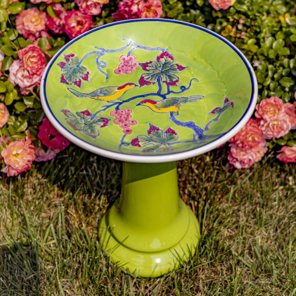 15 Inch tall green porcelain pedestal birdbath with love birds perched on a branch Laurel in front of rose bush