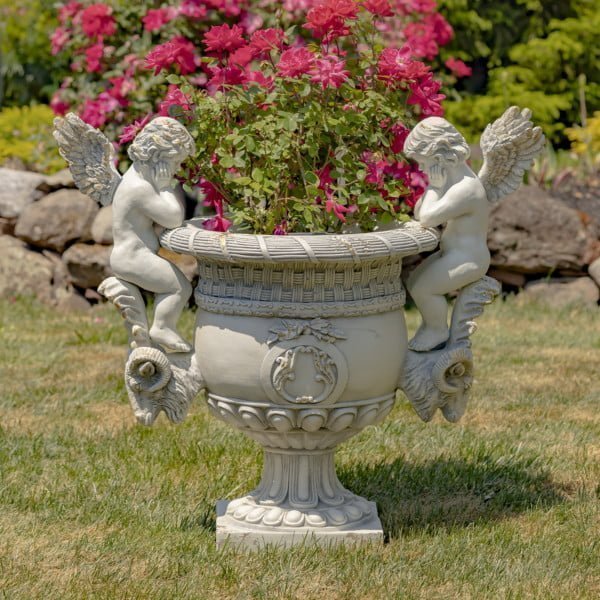 36.5 Tall Large Magnesium Urn with Cherubs in Antique Grey Amorini oustdie in front of rose bushes