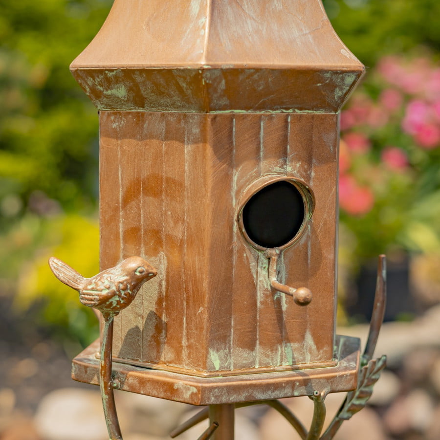 closed up image of iron birdhouse stake in antique copper hand-painted distressed finish with patina details with bell roof and little bird perched on decorative leaf