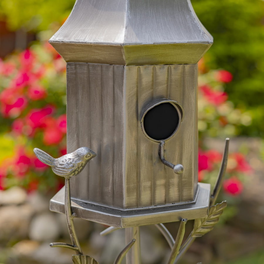 closed up image of iron bell roof birdhouse stake in antique silver hand-painted finish with little bird perched on decorative leaf