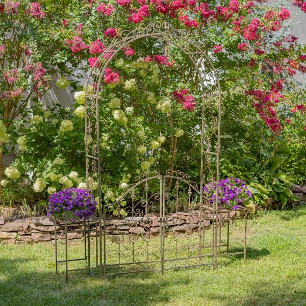 Iron Garden gate archway with 2 side Plant Stands with violet flowers on them in distressed antique bronze finish in garden