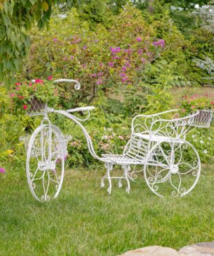 Large iron tricycle plant stand with flower baskets in antique white in garden