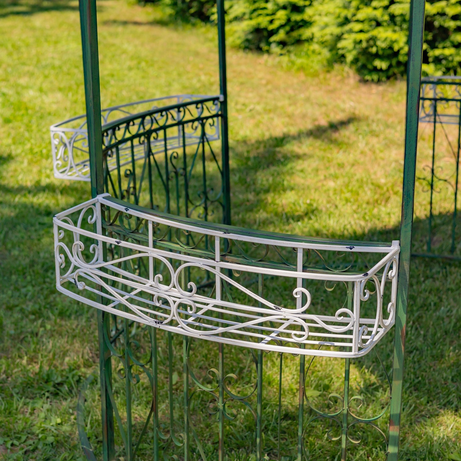 photo of ornate iron flower basket in white finish, attached to green gazebo