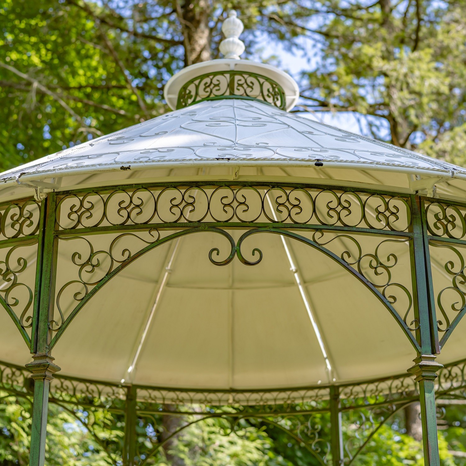 closed up image of green round gazebo with white conical roof, decorated with iron filigree details