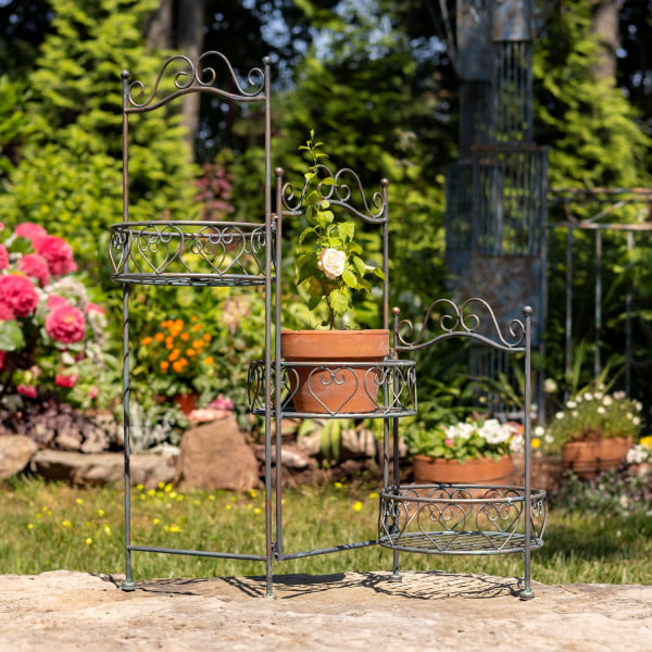 Iron tri-fold plant stand with three baskets in antique bronze finish standing in garden