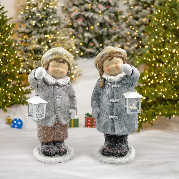 Pair of boy and girl standing in winter outfits holding lanterns Christmas statuary