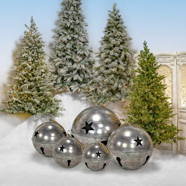 Set of 5 large sleigh bells with star cutouts in antique silver finish, 3 standing on faux snow and 2 hanging on rope