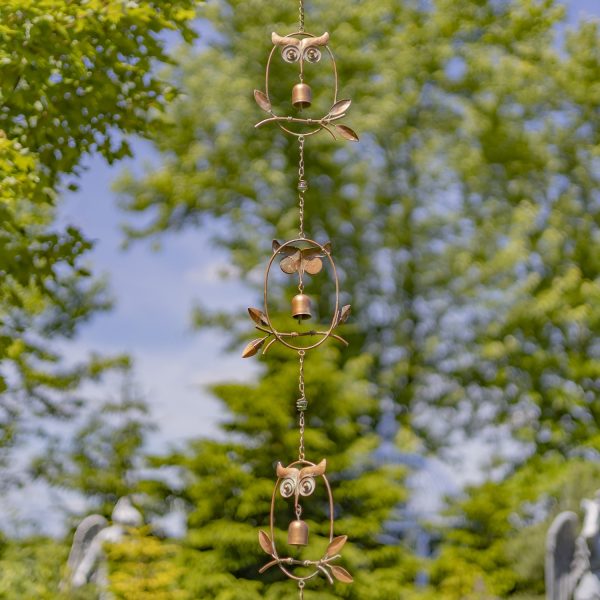 3 sections of iron rain chain in copper finish with owl and bell details hanging in garden