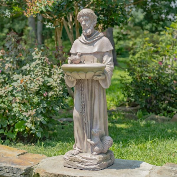 The statue shows a tall, gentle-looking man standing and holding a wide bowl in both hands. He has a beard and wears long, flowing robes like a monk. A bird sits on the edge of the bowl, and a squirrel is by his feet. The statue looks calm and peaceful, as if the man loves and cares for animals.
