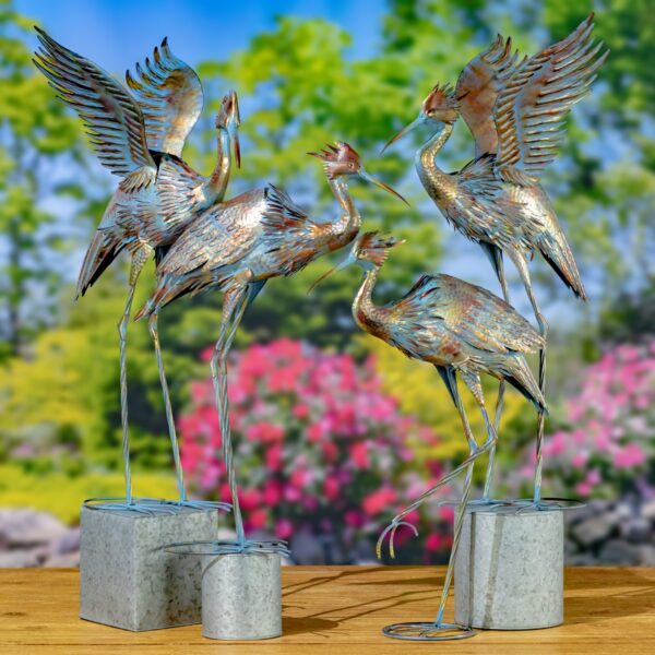 image display a set of four great blue heron metal garden figurines with an outdoor background